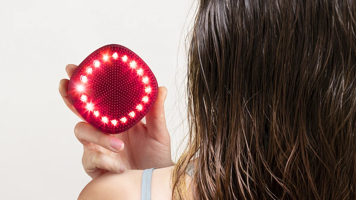 A woman with her back turned to us showing the back side of the FAQ 302 laser therapy for hair loss device